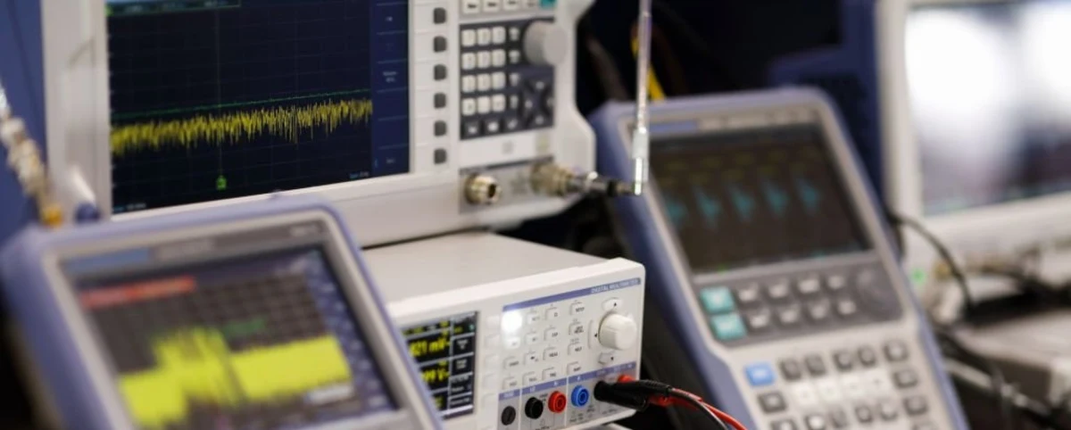 Banc de mesure RF AESTECHNO en gros plan : analyseur spectral Tektronix affichant la trace fréquentielle d'un module radio sous test, oscilloscope numérique en arrière-plan, sonde RF coaxiale connectée au DUT.