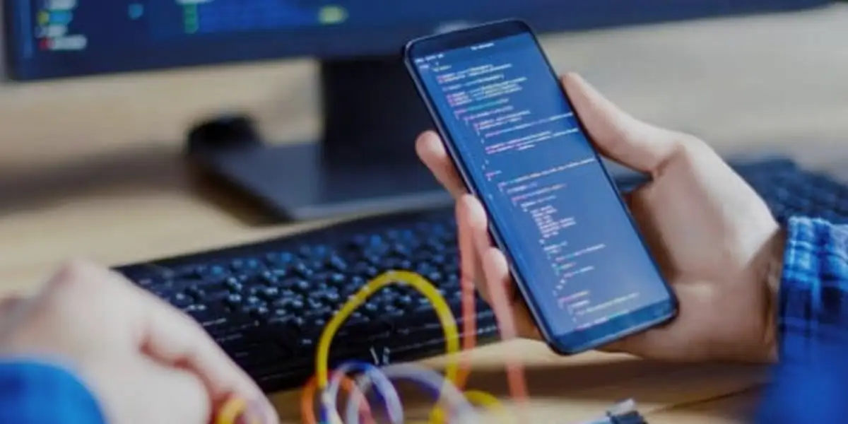 Ingenieur debogant un firmware sur breadboard avec smartphone : DevOps embarque en pratique.