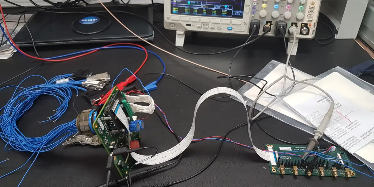 Banc d'analyse avec oscilloscope, cartes embarquées et faisceau de cables : situation typique de projet à reprendre.